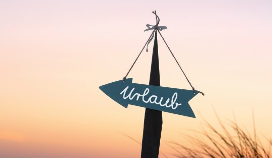 Strandschild in Pfeilform mit der Aufschrift Urlaub