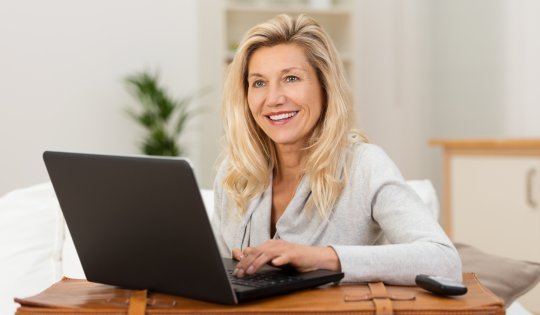 lächelnde frau bucht eine reise am laptop