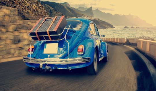 Retro car with luggage on the roof rack on the coastal road. Travel, vacation concepts.retro, vintage color